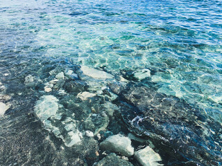 Transparent sea surface, lagoon, pebbles and stones, ripples on the sea surface