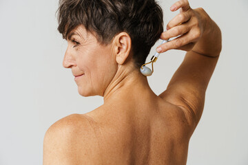 Mature half-naked woman massaging her neck with jade roller