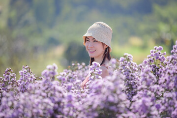 Young happy traveler Asian woman sightseeing on Margaret Aster flowers field in garden at Khao Kho, Thailand, relaxing on vacation concept