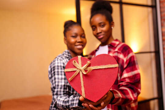 happy woman is making Valentine's Day gift to her beloved girlfriend at home at romantic night