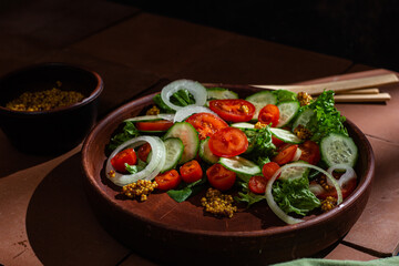 Vegetarian salad with cucumber, tomato and spinach in a plate