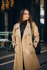 Fototapeta premium Young woman in coat walking by the cafe