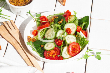Vegetarian salad with cucumber, tomato and spinach in a plate