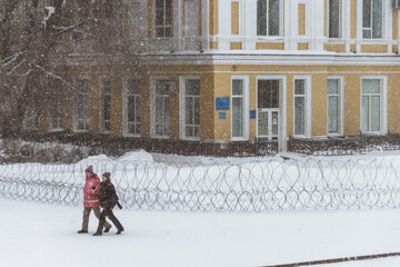 Uralsk, Kazakhstan, 6.01.2022 - people walk past the akimat building, which was surrounded by barbed wire, state of emergency in the country, rallies in Kazakhstan
