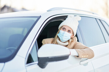 Happy woman driving car in snowy winter wearing mask