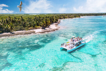aerial view of a boat on excursion from La Romana to Saona via Punta Cana heading along beautiful caribbean beaches, Dominican Republic - obrazy, fototapety, plakaty