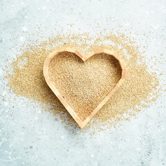 White quinoa. Set out in the form of a heart. On a gray stone background. Top view.