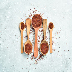 Healthy Organic Food. Dry brown quinoa in a wooden spoon. On a gray stone background. Top view.