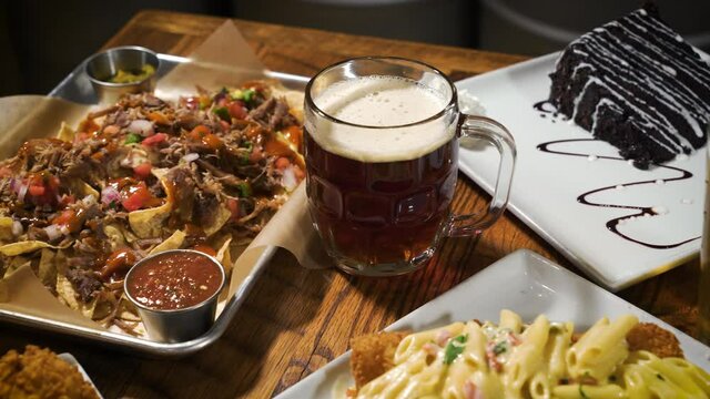 Plates of delicious comfort food and craft beer cover a brewery restaurant table, slider 4K