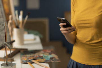 Artist working in the studio and chatting with her phone