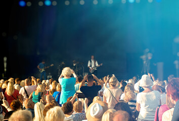 People enjoying musical concert on large stage.