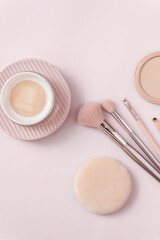 Make up layout, accessories and face powder on pastel pink background. Minimal and luxury make up, cosmetic or beauty salon composition. Flat lay, top view, copy space.