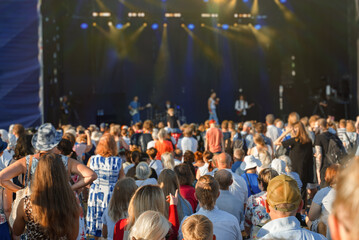People enjoying musical concert on large stage.