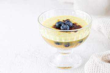 Homemade creme brulee with blueberries in a bowl on a light table. Sugar, gluten and lactose free and vegan.