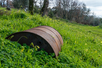 Rusting oil drum slowly sinking into the earth in a forest clearing