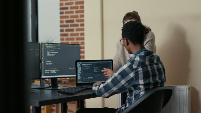 Two programmers doing high five hand gesture at desk with multiple screens running code celebrating successful algorithm. Software developers colleagues enjoying teamwork results in it agency