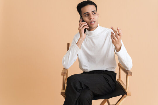 Young middle eastern man talking on cellphone while sitting on chair
