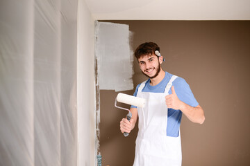 handsome young man professional painter in construction site wall painting renovation in a client house