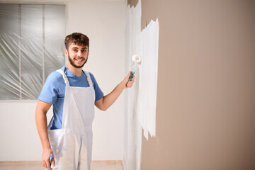 handsome young man professional painter in construction site wall painting renovation in a client house