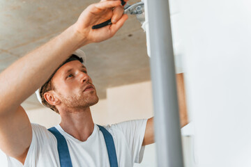 Repaiting the pipes. Young man working in uniform at construction at daytime