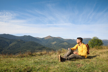 Fototapeta na wymiar Tourist with thermos and backpack enjoying beautiful mountain landscape