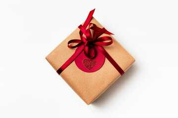 Elegant design of present gift box wrapped in brown craft paper with red ribbon and red tag