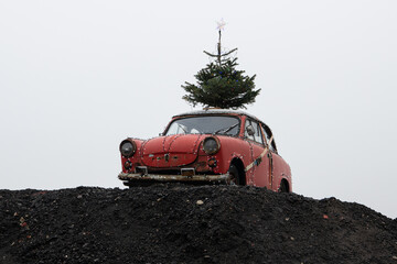 Ungewöhnliche Weihnachtsdekoration auf einem Erdhügel - Ein roter PKW  geschmückt mit  einem...