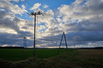 Fototapeta na wymiar cable lines on a farming field with cloudy blue sky