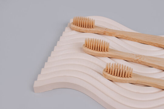 Trendy still life composition with natural bamboo toothbrushes on wavy plaster mold background with copy space. Sustainable lifestyle, zero waste home. Selective focus, mockup