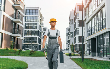 Finished buildings. Young man working in uniform at construction at daytime