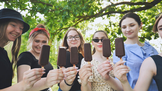 Friends Hold Chocolate Ice Cream On A Stick In A Row.