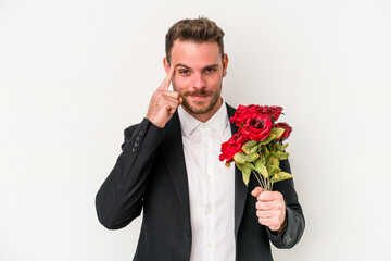 Young caucasian man holding bouquet of flowers isolated on white background pointing temple with finger, thinking, focused on a task.
