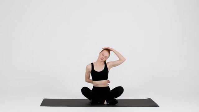 Athletic Young Woman Stretching Neck Muscles While Training In Studio
