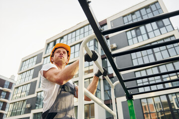 Looking far away. Young man working in uniform at construction at daytime