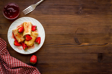Fototapeta na wymiar Hot rolled pancakes with strawberry and berry sauce