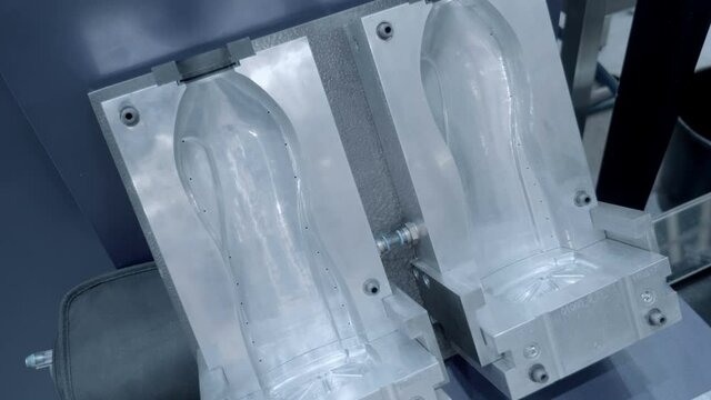 Industrial die for the manufacture of plastic bottles by injection blow moulding (injection stretch blow moulding, ISBM). Shot in motion. Closeup