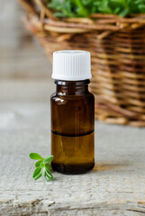 Small bottle with essential oil. Aromatherapy, spa and herbal medicine ingredients. Old wooden background.
