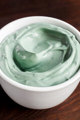 Blue (green) bentonite clay in a bowl. Clay texture close up. Diy mask and body wrap recipe. Natural beauty treatment and spa. Selective focus.