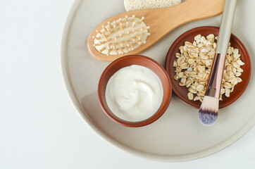 Fresh greek yogurt, oatmeal, make-up brush and wooden hairbrush. Natural beauty treatment and zero waste concept. Top view, copy space.