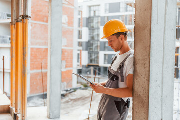 Resting indoors. Young man working in uniform at construction at daytime