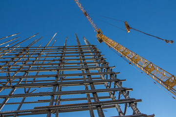 A reinforced steel rebar foundation work and tower crane against the blue sky. Construction. Building construction.