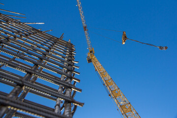 A reinforced steel rebar foundation work and tower crane against the blue sky. Construction....