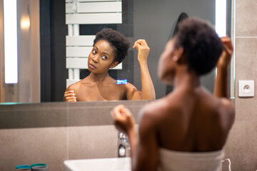 back of young african american woman adjusting hair in mirror - Powered by Adobe