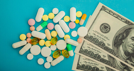 Money pills. Medicine pills on dollar bills on a blue background Covid-19 coronavirus pills are in one hundred dollar bills. The concept of insurance medicine, insurance, high cost high cost of drugs.