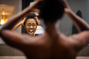 back of young african american woman adjusting hair in mirror and shouting - Powered by Adobe