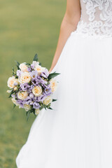 The bride's wedding bouquet of milk roses and lilac eustoms in the hands of the bride close-up