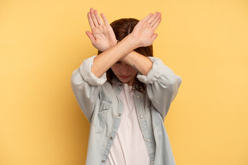 Young English woman isolated on yellow background keeping two arms crossed, denial concept.