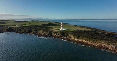 an aerial view of tarbat ness lighthouse on easter ross in the highlands of scotland near inverness showing blue sky and calm seas with the lighthouse dominating the scene and rocks