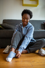 young African American woman siting on floor and putting on socks