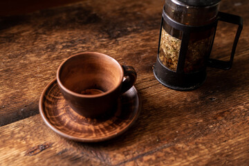 Empty clay tea cup. Dark wooden background. Teapot with herbal tea. Healthy herbal tea.